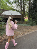 Rear view of a woman in a pink cable knit sweater with blonde hair