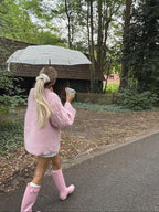 Rear view of a woman in a pink cable knit sweater with blonde hair