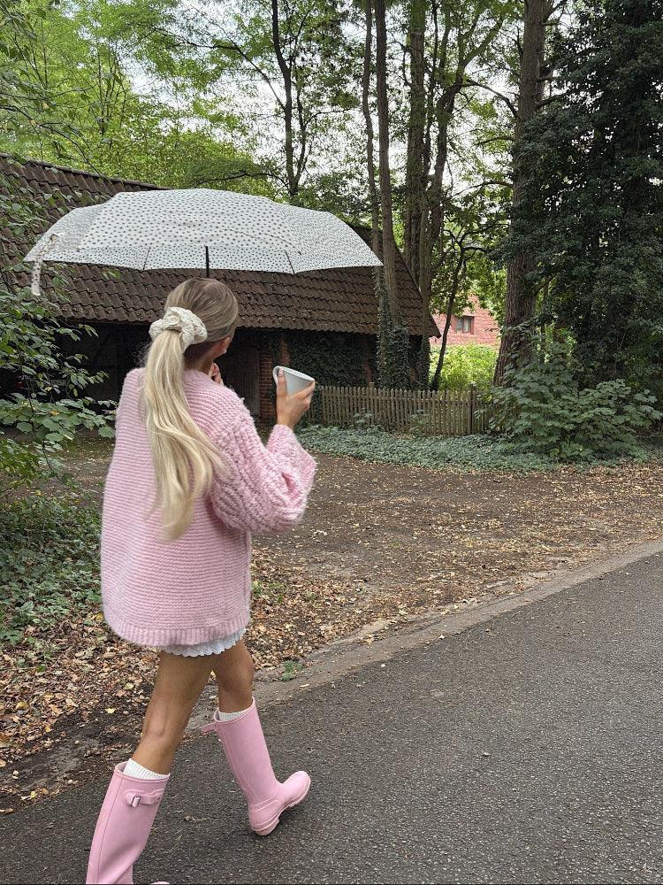 Rear view of a woman in a pink cable knit sweater with blonde hair