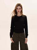 Woman wearing a black crew neck long sleeve cinched waist sweater