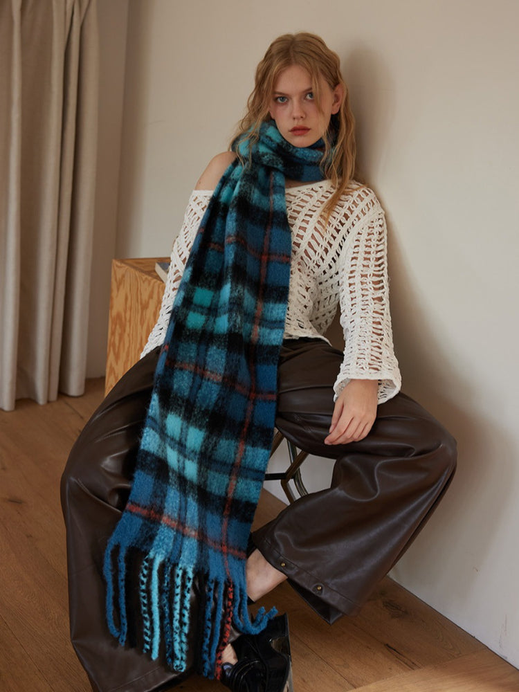 Model wearing blue plaid scarf with fringed ends