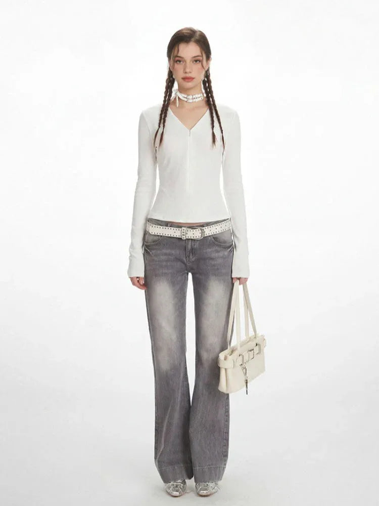 Woman wearing a white long-sleeve V-neck top and grey flared jeans