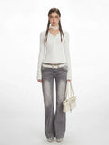 Woman wearing a white long-sleeve V-neck top and grey flared jeans