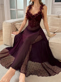 Woman wearing a sheer plum maxi slip dress with floral applique trim and lace detailing, sitting on a sofa.