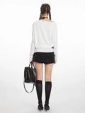 Back view of a model in a white long-sleeve top and black shorts.