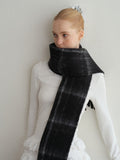 model posing with a long black and grey tartan scarf