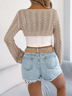Back view of a woman wearing a beige open-knit bolero over a white camisole.