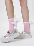 Pink crew socks with a plush white bunny charm and 'MSE' logo, worn with silver Mary Jane platform shoes.