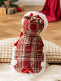 Rear view of a white dog in a red plaid pet coat with faux fur trim and decorative bows