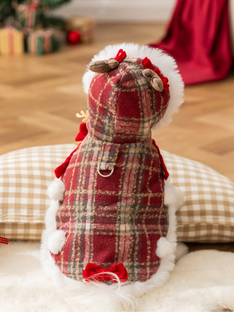 Rear view of a white dog in a red plaid pet coat with faux fur trim and decorative bows