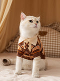 Cat wearing a brown and orange striped knit sweater with a lace-up front and cream collar.