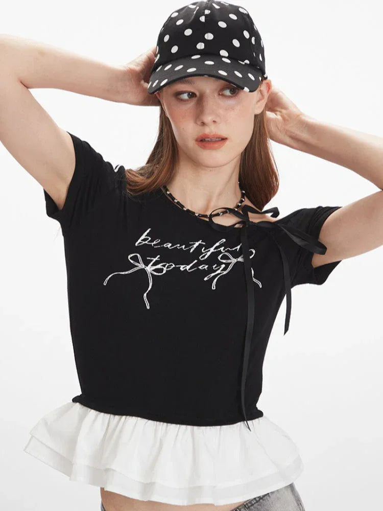 Detailed view of the graphic print and ruffle trim on the black cropped t-shirt.