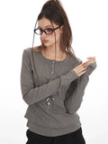 Woman posing with hands near waist in a grey faux layered henley top