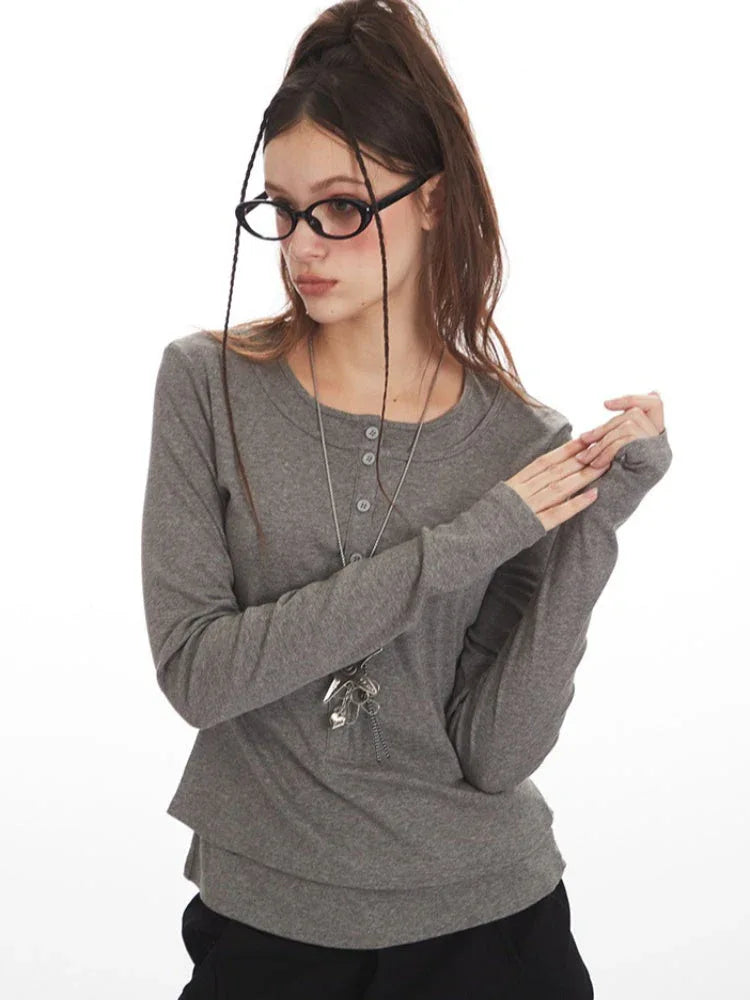 Woman posing with hands near waist in a grey faux layered henley top