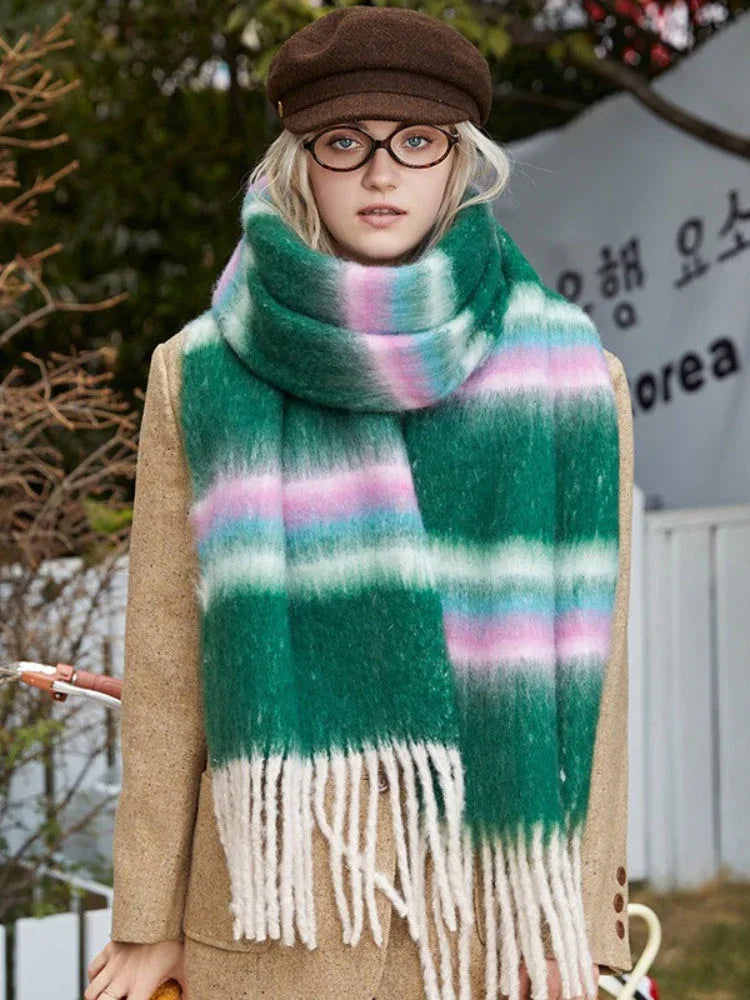 Woman wearing a tan coat and a green plaid scarf with white, pink, and blue stripes.