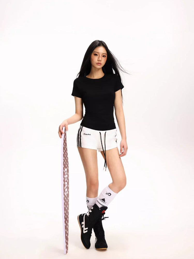 Woman wearing a black fitted short-sleeve t-shirt and white athletic shorts