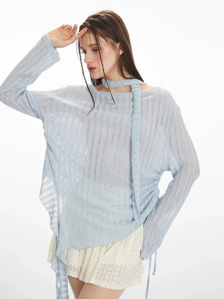 Model posing in a light blue ethereal shimmer knit top with a scarf
