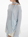 Full body shot of a woman in a light blue shimmering knit tunic with a scarf