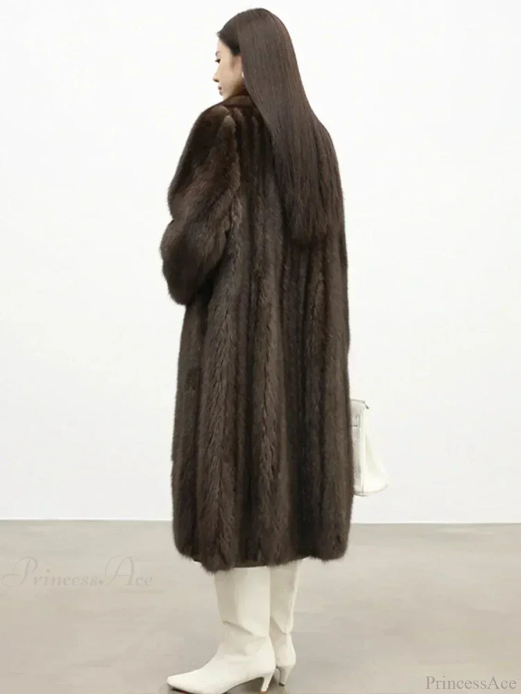 Rear view of a woman wearing a long brown mink fur coat and white boots.