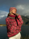 Woman wearing a pink floral knit turtleneck sweater with a pink beanie outdoors