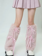 Close-up of pink faux fur leg warmers with ribbon ties on a person's legs.