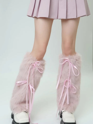 Close-up of pink faux fur leg warmers with ribbon ties on a person's legs.