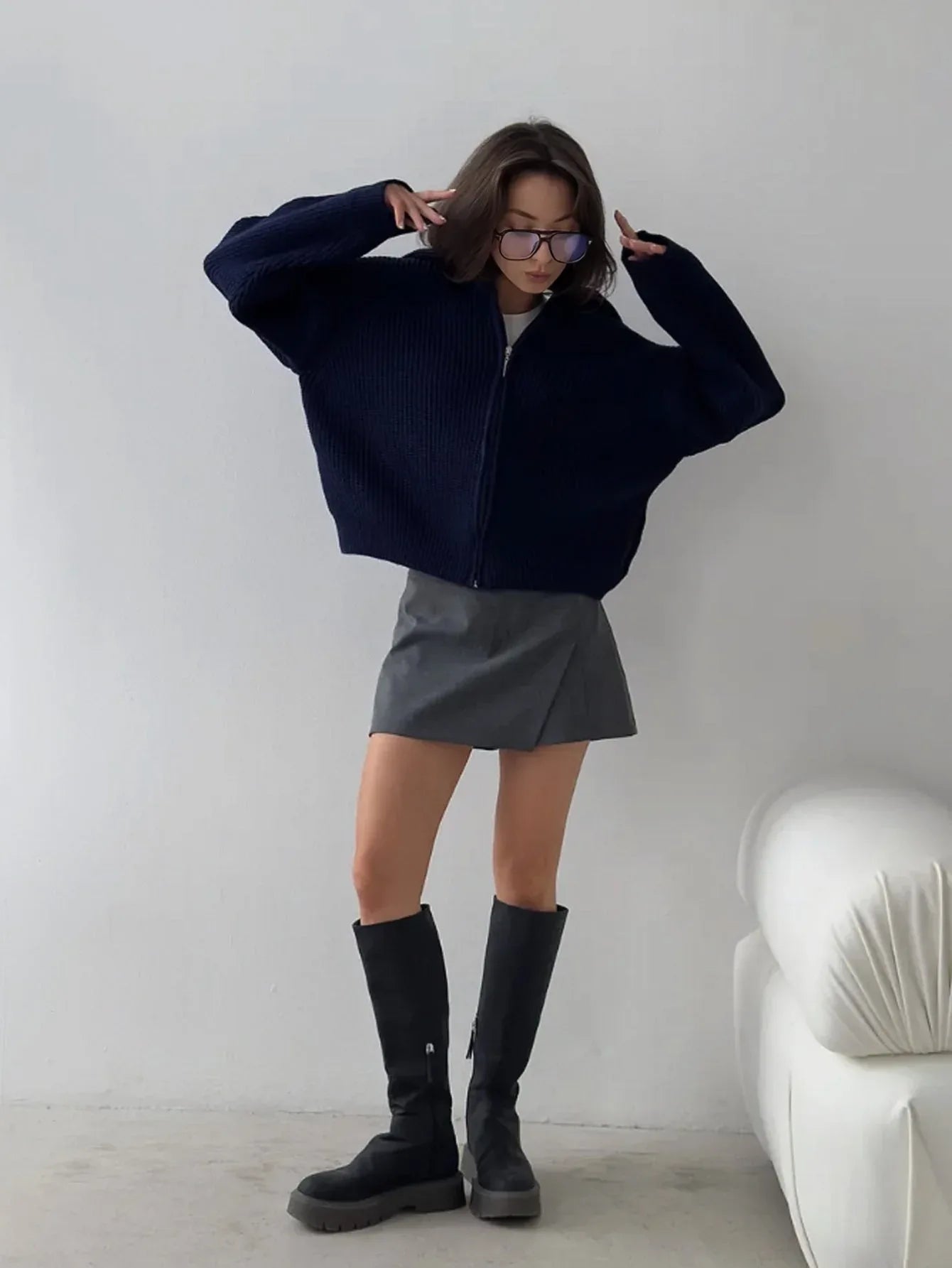 Woman wearing a navy blue ribbed knit zip-up jacket with a collared neckline and oversized sleeves.