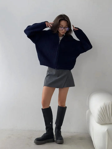Woman wearing a navy blue ribbed knit zip-up jacket with a collared neckline and oversized sleeves.
