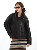 Woman wearing a black faux leather aviator jacket with shearling collar and lapel details, styled with sunglasses.