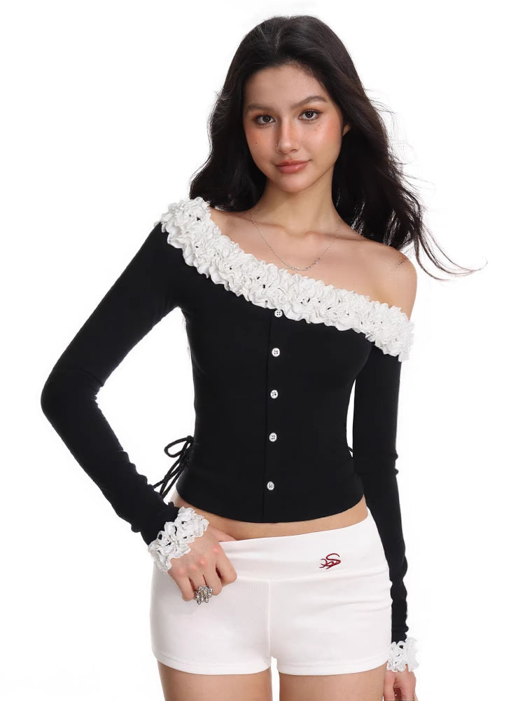 Woman posing in a black long-sleeved top with white ruffled trim, button front, and drawstring sides. The top is styled off-the-shoulder.