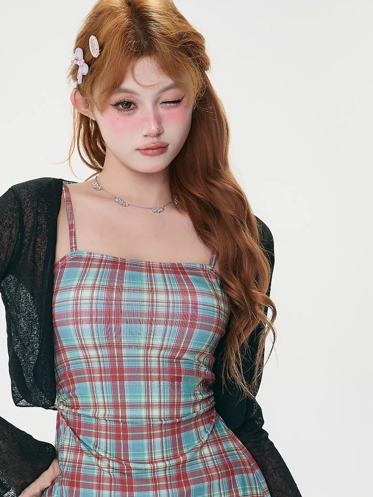 Woman wearing a black sheer bell sleeve cardigan over a red and blue plaid spaghetti strap mini dress.