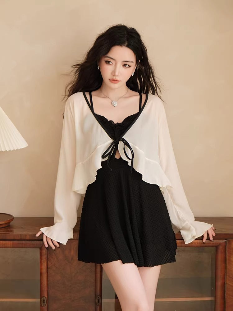 Woman wearing a black one-piece swimsuit with a white sheer cover-up.