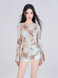 Woman wearing a long-sleeve tie-dye mesh top and matching shorts.