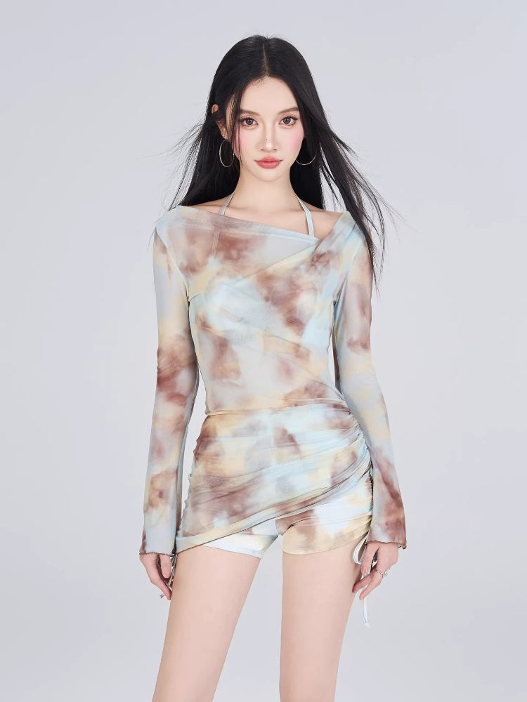Woman wearing a long-sleeve tie-dye mesh top and matching shorts.