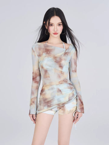 Woman wearing a long-sleeve tie-dye mesh top and matching shorts.