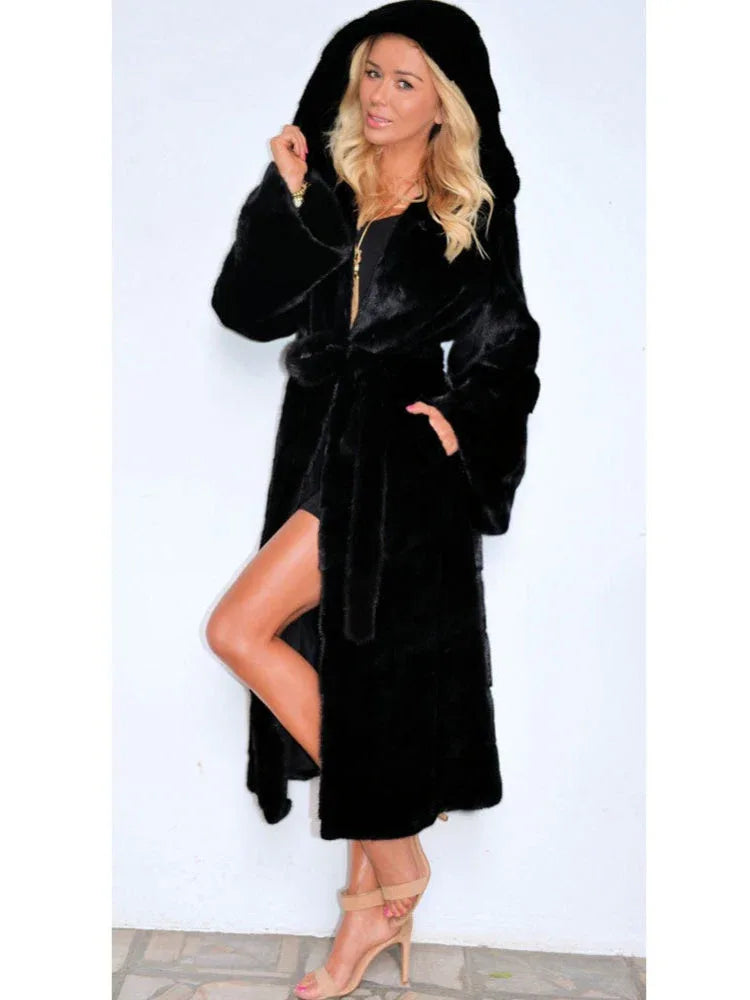Woman wearing a long black hooded faux fur coat with a belt