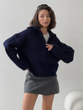 Woman posing in a navy blue ribbed knit zip-up jacket.