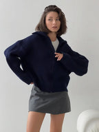 Woman posing in a navy blue ribbed knit zip-up jacket.