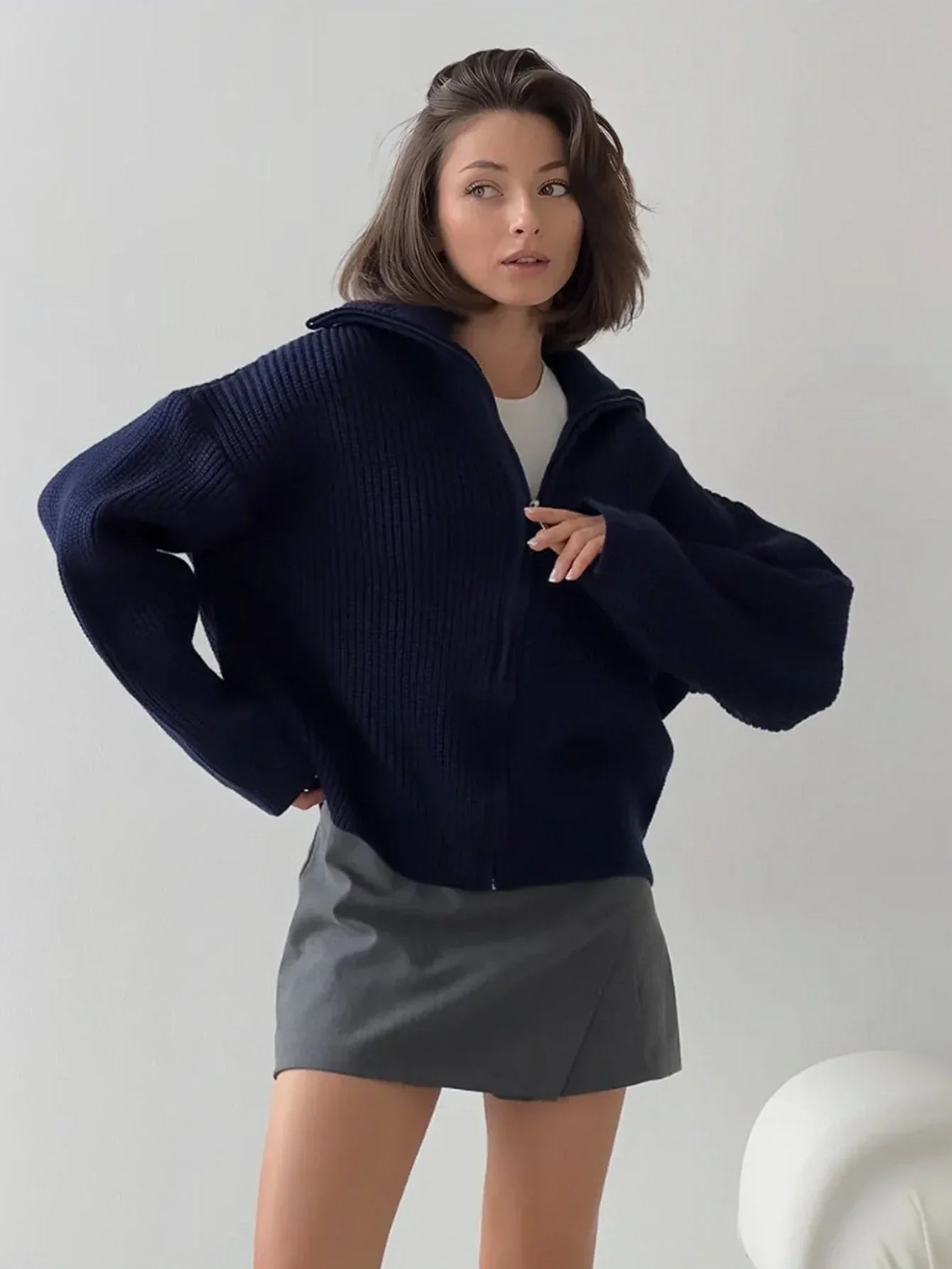 Woman posing in a navy blue ribbed knit zip-up jacket.