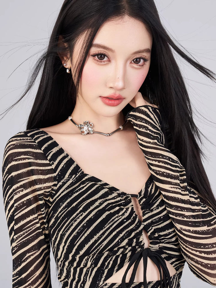 Close-up of the neckline and sleeve detail on a black and gold striped sheer mesh mini dress.