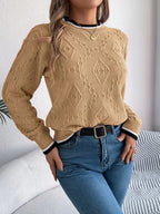 Front view of a woman in a tan geometric pattern sweater with blue jeans.
