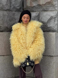 Woman wearing a yellow shaggy faux fur coat with a black headband and a black handbag with gold hardware.