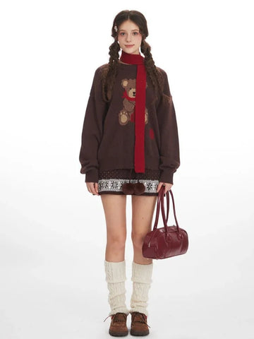 Woman wearing a brown oversized knit sweater with a teddy bear graphic and red scarf.