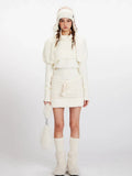 Woman wearing a cream knit turtleneck sweater with puffed sleeves over a cream knit mini skirt with a drawstring waist.