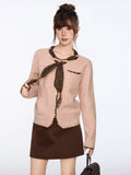 Close-up of the front of the pink knit cardigan, showing the button closure and scarf detail