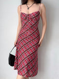 woman wearing a red and pink plaid mesh midi dress with spaghetti straps and a tie front detail