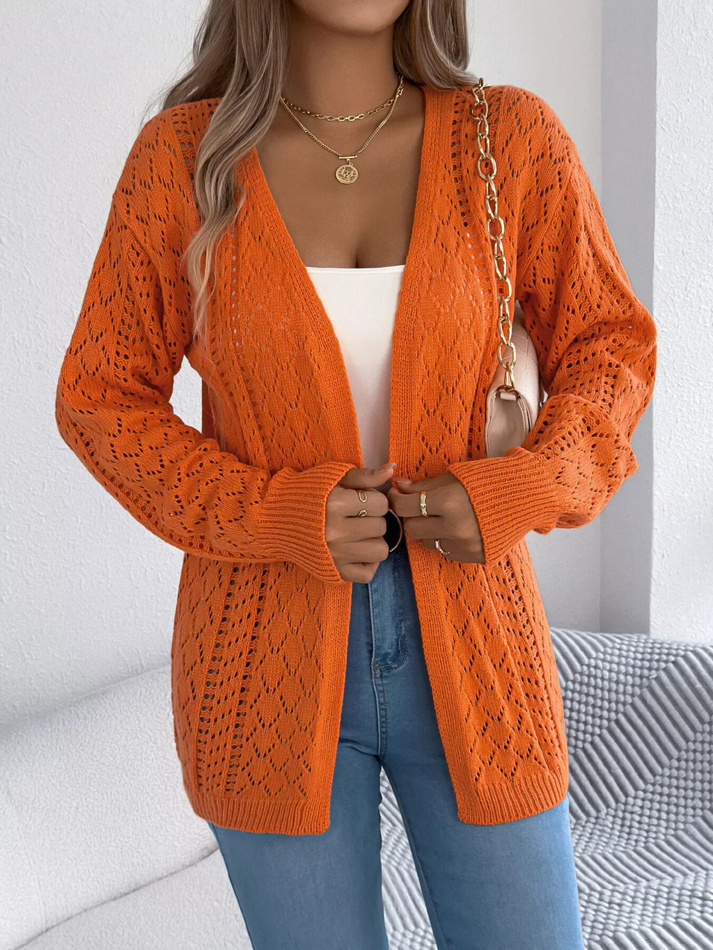 Front view of a woman wearing an orange open-knit cardigan, showcasing the open front and knit pattern.