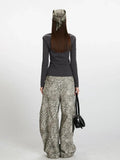 Back view of a woman wearing a dark grey long-sleeve ribbed knit top with a square neckline and buttoned placket, paired with grey leopard print wide-leg cargo pants and a black handbag.