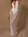 Woman wearing a white one-piece swimsuit with a plunging neckline and gold hardware, paired with a sheer white lace maxi skirt.