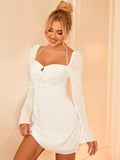 Woman posing in a white ruched dress with long bell sleeves.